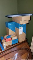 Stacked boxes showing three SimpliSafe Base Station boxes along with multiple smaller boxes likely containing motion sensors, keypads, and key fobs.