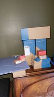 SimpliSafe security components stacked, showing 3 base station boxes and several smaller boxes on a wooden surface.
