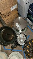 Photo showing stainless steel stock pot with lid, stainless steel mixing bowls, and metal colander.