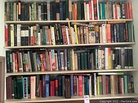 Four shelves filled with books of various sizes and colors, front view showing titles on spines, including works by Charles Fort and Graham Greene.