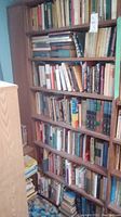 Photo of multiple shelves filled with books arranged vertically and stacked horizontally at the bottom.