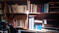 Bookshelves filled with various books, some with visible wear, alongside electronic items.