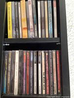 Two shelves of CDs side view showing various titles and artists including classical and popular music.