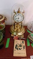 Original Kundo 400 day anniversary clock in glass dome with winding key and instruction card on table