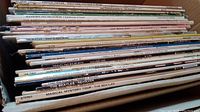 Partial box of LP vinyl records viewed from the side showing titles like The Beatles, Firesign Theatre, Chad Mitchell Trio, and others.