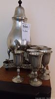 Photo of the pewter samovar with spigot, tray partially visible behind, and several cups in front
