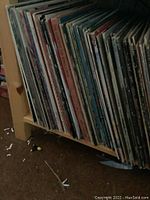Side view of a wooden shelf holding a row of vinyl albums with visible spines and covers, showing classical and opera album titles