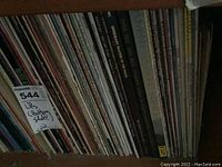 Photo of numerous classical music vinyl albums on a bottom wooden shelf, spines showing various artists and composers including Johann Sebastian Bach