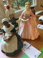 Front view of two Royal Doulton figurines side by side on table