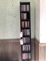 Single black CD shelving unit filled with CDs for size reference, with tags attached