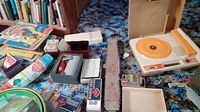 Overview photo showing the lot contents with books, cards, Fisher Price record player, toy cars, and other items.