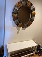 Front view of white bench below metal-framed round mirror.