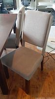Photo of a solid wood dining chair with grey fabric upholstery on seat and backrest.