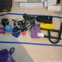Full view of various exercise equipment laid out, including pull up bars, weights, small exercise ball, resistance bands, and jump rope.