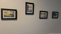 Four framed art prints on wall, varied landscape and house scenes