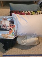 Shows reversible quilt packaged with floral design, along with two white pillows and wedge pillows below them.