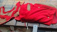 Red sari and blouse laid out showing the fabric and embellishments.