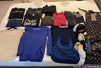 Overview of all clothing items laid out on a bed including tops, accessories, and casual wear.