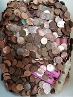 Overhead photo showing a large pile of mixed pennies, both loose and rolled in pink and white paper rolls.