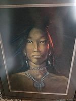 Photo of framed original pastel portrait showing a native person wearing traditional jewelry and posed against dark background.