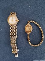 Two vintage ladies' wristwatches including a Citizen Eco-Drive silver and gold-tone watch and a smaller gold-tone wristwatch with linked bracelet band on dark background.
