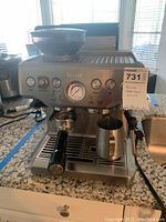 Front view showing bean hopper with beans, control panel with gauge, portafilter inserted and milk pitcher on drip tray