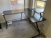 Full view of the wooden L-shaped corner desk showing desk surface, metal frame, and elevated platform.