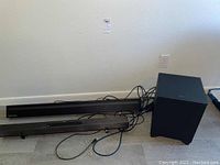 Photo of Samsung and Sony soundbars and subwoofer units arranged on floor with visible wires.