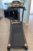 Front angled view of treadmill showing digital display, handrails, and running belt.