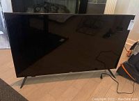 Front view of RCA Roku flatscreen TV on stand, screen off