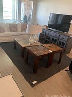 Photo of the rug placed on floor in living room setting next to sofa and furniture, displaying size, color and texture.