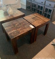 Pair of heavy wood stained square end tables with scratches, placed on a dark rug in a living room setting.