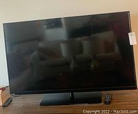Front view of Toshiba flat screen TV on stand, screen off showing black reflective surface, TV and stand in good condition.