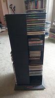 Black plastic swivel rack filled with CDs and cassettes shown from side angle