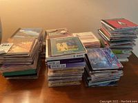 Multiple stacks of CDs with assorted genres like Irish, relaxation, country, and rock