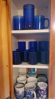 Cobalt blue glassware on upper two shelves including mugs and tumblers