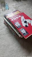 Stack of various Black Belt and Official Judo magazines on carpeted floor.