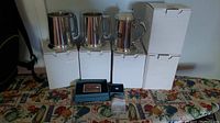Eight pewter tankards displayed on boxes with some additional small items and packaging.