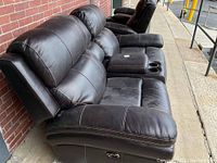 Side view of the brown leather power reclining loveseat showing padded armrest, stitching, and reclining mechanism.