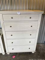 Front view of white 5-drawer chest showing brushed nickel knobs and general condition.