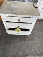 Front view showing three drawers with brushed nickel hardware, one drawer slightly open, and power cord visible on the side.