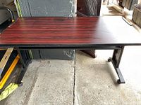 Full view of black brown metal desk with reddish formica top showing overall condition and surface detail.