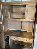 Full view of oak desk system with two side cabinets, open middle shelf, and keyboard tray with visible surface wear and smoke damage.