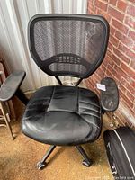 Front view of black office chair showing mesh back, padded seat with visible stains and dirt, and left armrest.