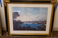 Full view of the framed Port of Baltimore 1836 print hung against a wall, showing the gold frame and matting.