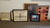 Five framed prints arranged on floor showing cathedral, maps, portrait, and abstract print