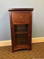 Front view of wooden cabinet with glass door and top drawer, showing general condition and finish.