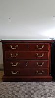 Front view of wooden file cabinet with glass top and three drawers with gold-colored handles.