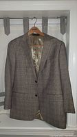 Light checkered men's suit jacket hung on a hanger against a light background.