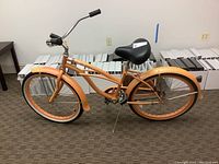 Side view showing orange gradient frame, matching painted rims and fenders, Firmstrong black seat, and parking stand.